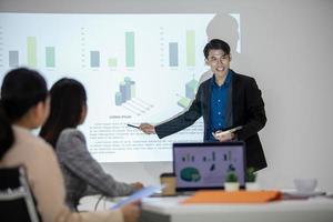 des collègues masculins et féminins de l'équipe commerciale asiatique qui parlent au travail partagent des idées avec un tableau à bord, de jeunes collègues de présentation heureux travaillent ensemble à bord. photo