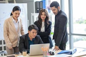 équipe commerciale asiatique collègues masculins et féminins parlant au travail partagent des idées avec un ordinateur portable, des collègues heureux travaillent ensemble sur un ordinateur au bureau. photo