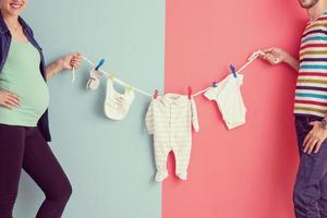 jeune couple tenant des combinaisons de bébé photo