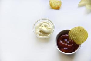 croustilles ondulées au poivre sur fond blanc. délicieuses frites de restauration rapide. avec de la sauce. photo