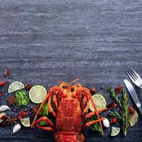homard bouilli cuit, délicieux dîner repas de fruits de mer avec couteau et fourchette sur fond d'ardoise en pierre noire, conception de menus de restaurant, vue de dessus, frais généraux photo