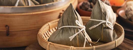 boulette de riz, zongzi - boulette de riz chinois zongzi dans un bateau à vapeur sur une table en bois avec brique rouge, fond de fenêtre à la maison pour le concept de festival de bateaux-dragons, gros plan.