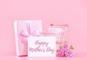 concept de conception de cadeau de fête des mères, bouquet de fleurs d'oeillets roses avec boîte enveloppée isolée sur fond rose clair, espace de copie. photo
