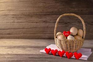 oeufs dans un panier en osier en forme de coeur sur une table en bois photo