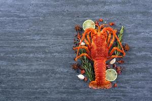 homard bouilli cuit, délicieux dîner repas de fruits de mer avec couteau et fourchette sur fond d'ardoise en pierre noire, conception de menus de restaurant, vue de dessus, frais généraux photo