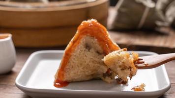 boulette de riz zongzi manger - jeune femme asiatique mange de la nourriture traditionnelle chinoise sur une table en bois à la maison pour la célébration du festival du bateau-dragon, gros plan photo