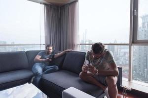 deux jeunes hommes utilisant un téléphone portable à la maison photo