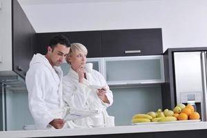 couple heureux lisant le journal dans la cuisine au petit déjeuner photo