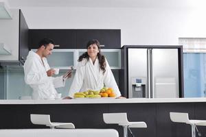 couple heureux lisant le journal dans la cuisine au petit déjeuner photo