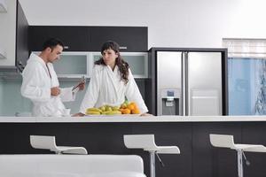 couple heureux lisant le journal dans la cuisine au petit déjeuner photo