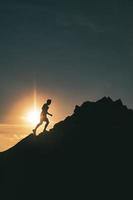 un homme court parmi les rochers dans un coucher de soleil de montagne coloré