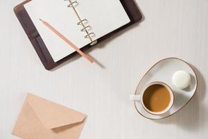 cahier propre, tasse de café et macaron coloré sur la vue de dessus de bureau gris. petit déjeuner confortable le matin. mise à plat de la mode. macarons sucrés. photo