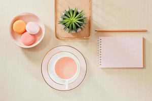 table de bureau beige de style photographie de stock avec cahier vierge, macaron, fournitures et tasse à café photo