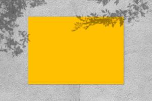 maquette d'affiche carrée jaune vide avec ombre légère sur fond de mur de béton gris.