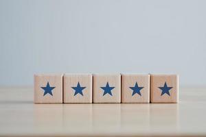 cinq étoiles sur la forme de cube de bloc de bois. satisfaction, commentaires, avis, le meilleur concept d'expérience client d'évaluation des services aux entreprises. photo
