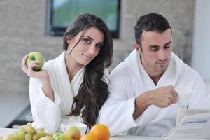 couple heureux lisant le journal dans la cuisine au petit déjeuner photo