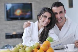 couple heureux lisant le journal dans la cuisine au petit déjeuner photo