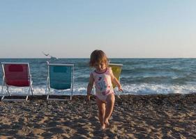 petite fille assise sur le sable et jouant avec un seau et une bêche sur la plage de la mer par une chaude journée d'été ensoleillée. fermer. vue de côté. photo