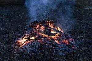 bois de chauffage fumant sur des cendres dans le crépuscule bleu photo