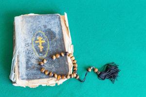 Perles d'inquiétude et vieux livre d'église sur table verte photo