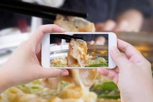 femme prenant une photo de sukiyaki shabu shabu