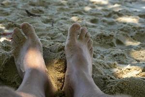 pieds sur le sable de la plage à l'ombre des arbres photo