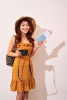 femme touristique expressive en vêtements décontractés d'été, chapeau tenant un passeport, billets isolés sur fond beige. femme voyageant à l'étranger pour voyager le week-end. concept de voyage en avion photo