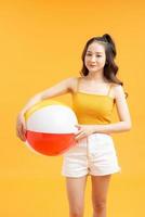 Adolescente souriante avec ballon de plage sur fond jaune photo