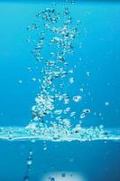 image de fond abstrait de bulles dans l'eau. eau propre avec des gouttelettes d'eau et des vagues. eau douce un verre avec fond bleu bulles. photo