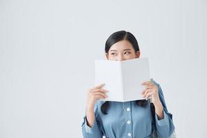 joyeuse fille brune couvre son visage avec son cahier blanc photo