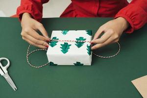 gros plan sur les mains d'une femme emballant un cadeau de noël photo