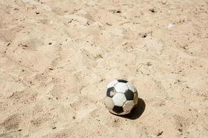 balle unique sur la plage avec personne. balle classique cassée sur le sable. résumé de la vie de passe-temps et de sport. photo