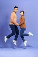 photo d'un jeune couple d'amoureux heureux et excité sautant isolé sur fond violet.