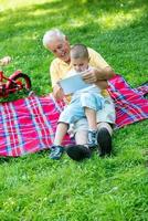 grand-père et enfant dans le parc à l'aide d'une tablette photo