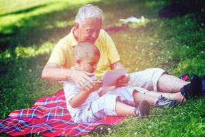 grand-père et enfant dans le parc à l'aide d'une tablette photo