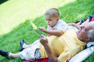 grand-père et enfant dans le parc à l'aide d'une tablette photo