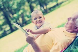 grand-père et enfant dans le parc à l'aide d'une tablette photo