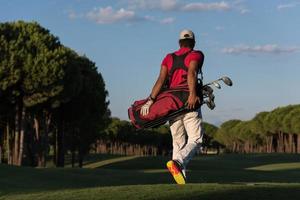 golfeur marchant et portant un sac de golf photo