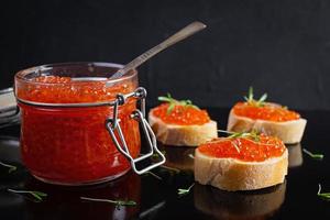 délicieux caviar rouge frais avec des toasts de baguette sur fond sombre