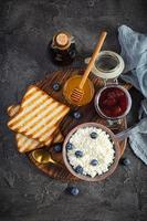 délicieux fromage cottage avec myrtille, miel, confiture de fraises et pain grillé. petit-déjeuner sain. vue de dessus photo