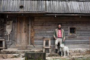 Hipster avec chien devant une maison en bois photo