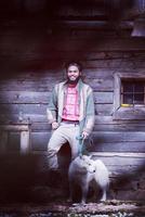 Hipster avec chien devant une maison en bois photo