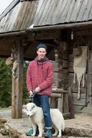 jeune hipster avec chien devant une maison en bois photo