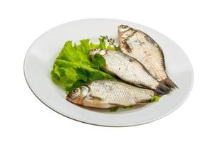 poisson carassin sur la plaque et fond blanc photo