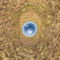 inversion de la petite planète bleue transformation du panorama sphérique à 360 degrés. vue aérienne abstraite sphérique sur champ jaune avec de beaux nuages impressionnants. courbure de l'espace. photo