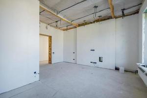 chambre vide non meublée avec un minimum de réparations préparatoires. intérieur avec murs blancs et cloisons sèches photo