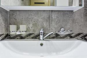 lavabo en céramique avec robinet avec distributeurs de savon et de shampoing dans une salle de bain ou une cuisine loft coûteuse photo