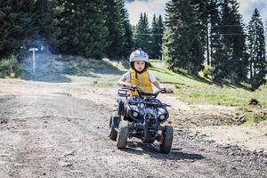 petit garçon apprenant à conduire un quad à quatre roues sur un chemin de terre. photo