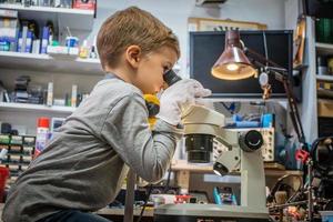 petit garçon regardant à travers un microscope dans un laboratoire technologique. photo
