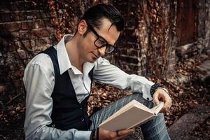 homme d'âge moyen souriant lisant un livre à l'extérieur. photo